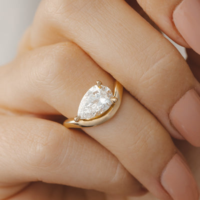 Gold ring with a pear-shaped diamond on a hand