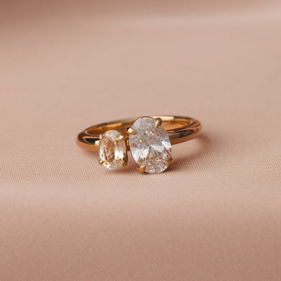 Gold ring with two diamonds on a beige fabric background